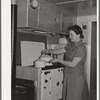 Wife of aircraft worker at the stove in her trailer home at the FSA (Farm Security Administration) camp for defense workers. San Diego, California