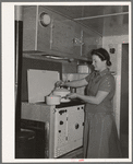 Wife of aircraft worker at the stove in her trailer home at the FSA (Farm Security Administration) camp for defense workers. San Diego, California