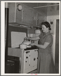 Wife of aircraft worker at the stove in her trailer home at the FSA (Farm Security Administration) camp for defense workers. San Diego, California