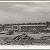 Working on jigs, with dormitories in the background at the FSA (Farm Security Administration trailer camp for defense workers. The dormitories at this project will accomodate, when finished, 952 single men. Dormitory residents will pay five dollars weekly