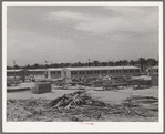 Working on jigs, with dormitories in the background at the FSA (Farm Security Administration trailer camp for defense workers. The dormitories at this project will accomodate, when finished, 952 single men. Dormitory residents will pay five dollars weekly