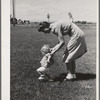 Farm worker's wife teaches her baby girl to walk at the FSA (Farm Security Administration) labor camp. Caldwell, Idaho