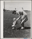 Farm worker's wife teaches her baby girl to walk at the FSA (Farm Security Administration) labor camp. Caldwell, Idaho
