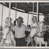 Father with his two daughters on the merry-go-round, one of the carnival attractions at the Fourth of July celebrations