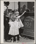 Little girls getting tickets for the merry-go-round at the carnival on the Fourth of July. Vale, Oregon
