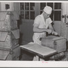 Putting layer of waxed paper over tub of butter at the Dairymen's Cooperative Creamery. Caldwell, Canyon County, Idaho