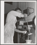 Taking a sample of milk to determine butter fat content. Dairymen's Cooperative Creamery. Caldwell, Canyon County, Idaho