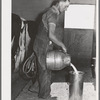 Member of the Dairymen's Cooperative Creamery pours up fresh milk. Notice the electric milking apparatus in his left hand. Caldwell, Canyon County, Idaho