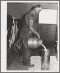 Member of the Dairymen's Cooperative Creamery pours up fresh milk. Notice the electric milking apparatus in his left hand. Caldwell, Canyon County, Idaho