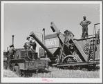 Combine and tractor are refueled in wheat field. Eureka Flats, Walla Walla County, Washington. Three men operate the tractor and combine