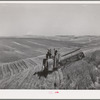 Combine in the wheat. Whitman County, Washington. About ninety percent of the land in this county is under cultivation. Wheat and livestock are principal crops