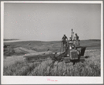 Caterpillar-drawn combine working in the wheat fields of Whitman County, Washington