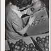 Farm woman who lives at the FSA (Farm Security Administration) farm family migratory labor camp, Yakima, Washington, packing wooden apples at the WPA (Work Projects Administration) apple packing school at the camp