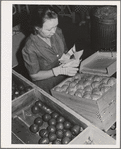 Farm woman who lives at the FSA (Farm Security Administration) farm family migratory labor camp, Yakima, Washington, packing wooden apples at the WPA (Work Projects Administration) apple packing school at the camp