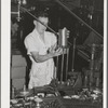 Feeding lids to machine which also seals the cans of salmon. Columbia River Packing Association. Astoria, Oregon