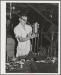 Feeding lids to machine which also seals the cans of salmon. Columbia River Packing Association. Astoria, Oregon