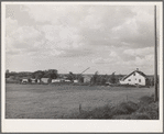 Trailers and other forms of temporary housing for workmen at the Umatilla ordnance depot ground near a farmhouse. Hermiston, Oregon. Workmen at the depot established temporary housing near sources of water
