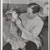 FSA (Farm Security Administration) dentist looking at the teeth of a young migrant child who lives at the FSA camp for farm families at Caldwell, Idaho