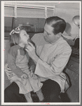 FSA (Farm Security Administration) dentist looking at the teeth of a young migrant child who lives at the FSA camp for farm families at Caldwell, Idaho