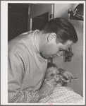 FSA (Farm Security Administration) dentist and migrant child in the FSA dental trailer at the FSA camp for farm families, Caldwell, Idaho