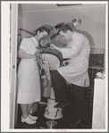 FSA (Farm Security Administration) dentist and nurse with migrant child in the FSA dental trailer at the FSA camp for farm families. Caldwell, Idaho