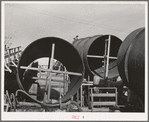 Segments of penstock pipe which will be used to transport water from reservoir formed by Shasta Dam to hydroelectric turbines. Notice the worker on top pipe; he is welding segments together. Shasta County, California