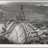 Shasta Dam under construction. Cable cars carrying materials operate from the high tower. Shasta County, California