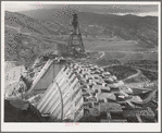 Shasta Dam under construction. Cable cars carrying materials operate from the high tower. Shasta County, California