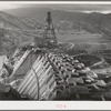 Shasta Dam under construction. Cable cars carrying materials operate from the high tower. Shasta County, California