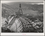 Shasta Dam under construction. Cable cars carrying materials operate from the high tower. Shasta County, California