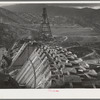 Shasta Dam under construction. Cable cars carrying materials operate from the high tower. Shasta County, California