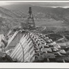 Shasta Dam under construction. Cable cars carrying materials operate from the high tower. Shasta County, California