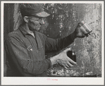 Workman with samples of "soap" oil made from olives. The "soap" oil is a thick, dark green oil. Strathmore, California