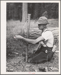 Grant County, OR. Malheur National Forest. Lumberjack making a "rubberman". It is used when a lumberjack who is sawing down a tree does not have a partner. The cross-saw is attached to the heavy rubber belt which holds saw secure while one man saws