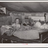 Child sitting on bed in tent home near Sallisaw, Oklahoma. Sequoyah County