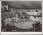 Child sitting on bed in tent home near Sallisaw, Oklahoma. Sequoyah County