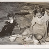 Migrant children eating under tarpaulin stretched from their automobile parked near Muskogee, Oklahoma. Muskogee County