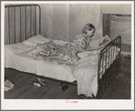 Daughter of woman tenant farmer reading magazine. Near Sallisaw, Oklahoma