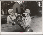 Pouring water into radiator of migrant's car in the streets of Muskogee, where family has stopped to say goodbye to their friends in that town. Oklahoma