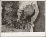 Migrant boy who is somewhat of a mechanic checking up the lighting wires of their improvised truck which will carry them to California. Near Muskogee, Oklahoma