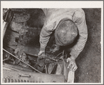 Migrant boy who is somewhat of a mechanic checking up the lighting wires of their improvised truck which will carry them to California. Near Muskogee, Oklahoma