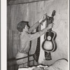 Migrant boy removing guitar before they leave for California. At old homestead near Muskogee, Oklahoma