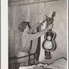 Migrant boy removing guitar before they leave for California. At old homestead near Muskogee, Oklahoma