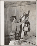 Migrant boy removing guitar before they leave for California. At old homestead near Muskogee, Oklahoma