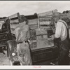 Placing the family chest into the rear of improvised truck which will take the Thomas family as migrants to California from Muskogee, Oklahoma