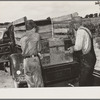 Placing the family chest into the rear of improvised truck which will take the Thomas family as migrants to California from Muskogee, Oklahoma
