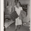 Mrs. Elmer Thomas, migrant to California, taking the blankets for packing into truck enroute to California from Muskogee, Oklahoma