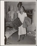 Mrs. Elmer Thomas, migrant to California, taking the blankets for packing into truck enroute to California from Muskogee, Oklahoma