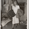 Mrs. Elmer Thomas, migrant to California, taking the blankets for packing into truck enroute to California from Muskogee, Oklahoma