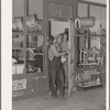 Migrant family emerging from grocery store where they have stopped along the road in order to buy bread and potatoes, which will form the basis for their noonday meal. Near Henryetta, Oklahoma